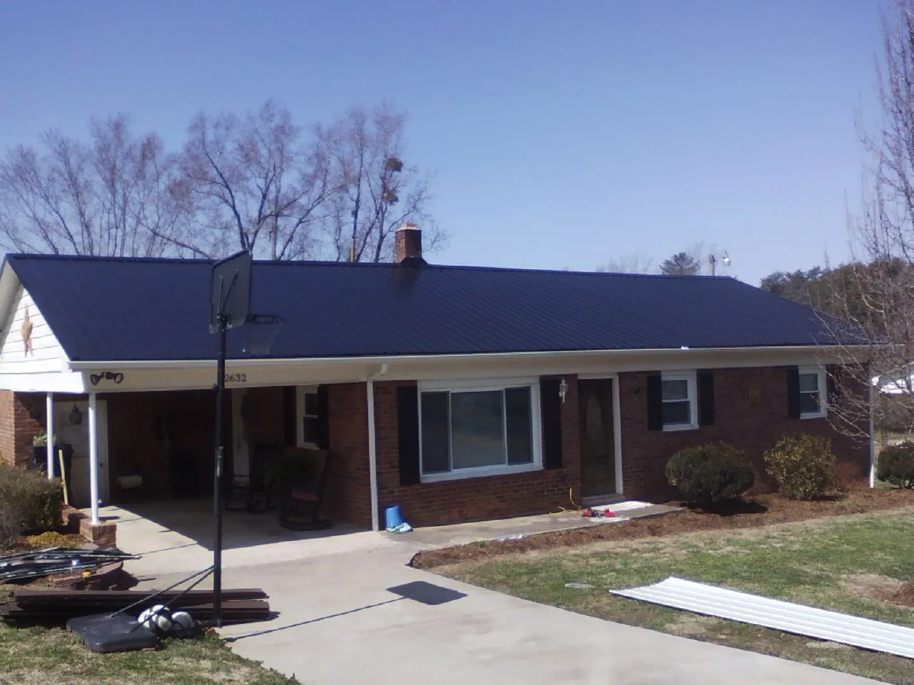 Finished dark blue metal roof on a brick ranch with a carport in Oxford