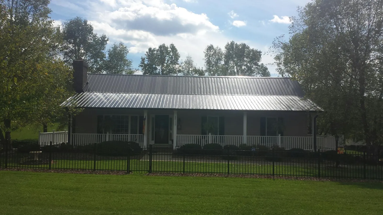 Gray metal roof on a brick ranch with a full width front porch — Gutter Guard Installation work by our crew in Oxford